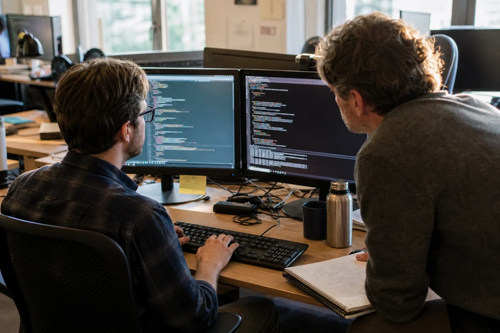 Backend developers working side by side at their code workstations