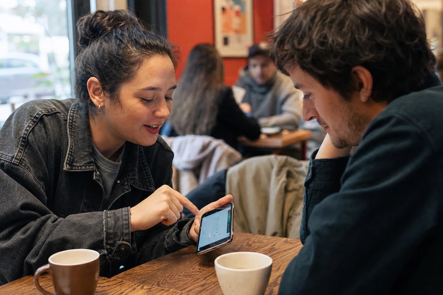 Mobile product teammates testing a working app together in a neighborhood cafe