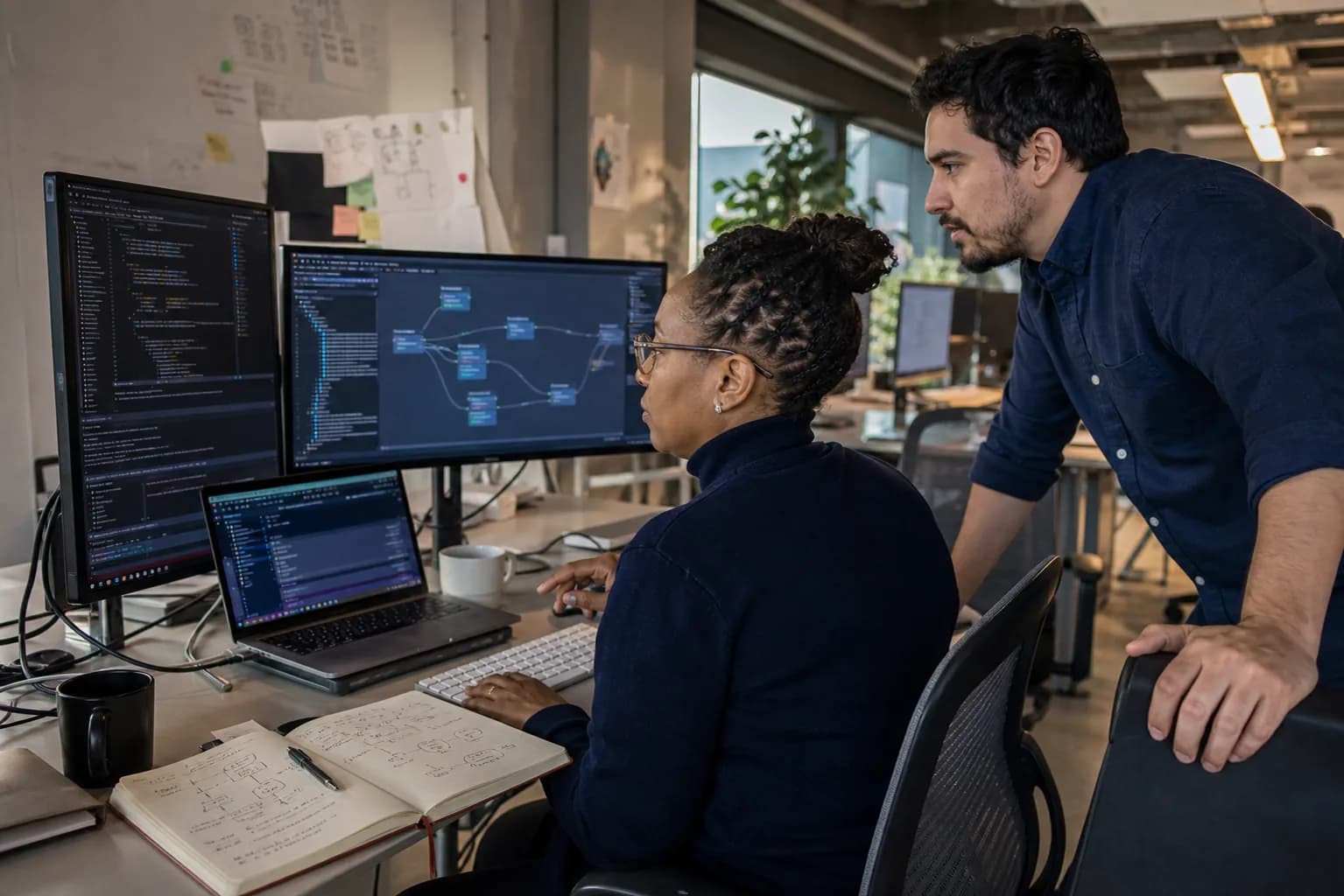 Two software engineers reviewing integration code and a system workflow at their workstation